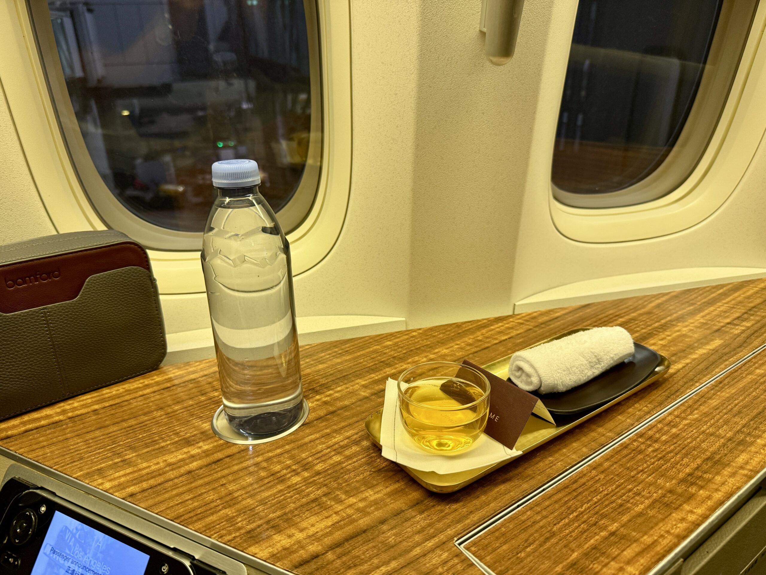 Aging Like a Fine Wine: Cathay Pacific First Class 777 Review 28 water bottle and tray with glass, note, and rolled up towel