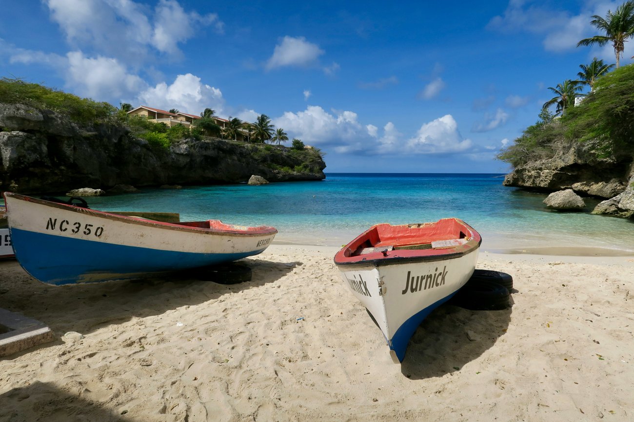 The Extra Mile, July 15: Pick Up the Phone to Book Business Class & More 4 two boats on the beach next to the ocean with houses in the distance