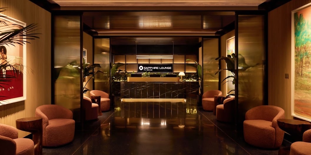 Chase Sapphire Lounge (DFW) check-in desk/entrance with mood lighting, wood paneling, artwork on the walls, and a small sitting area