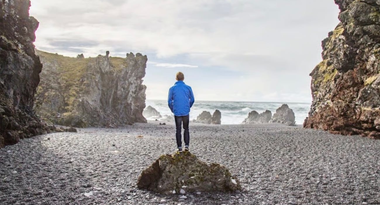 The Extra Mile, July 24: A Trick for Cheap Flights to Hawaii, Hong Kong from 29K SkyMiles Roundtrip & More 5 Thrifty Traveler's Gunnar Olson, standing on a rock looking out at the water, in Iceland.