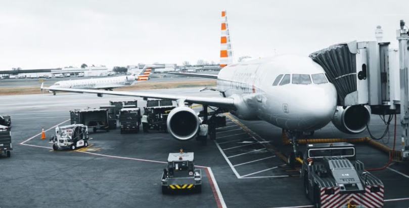 American Airlines plane sitting at gate with baggage carts