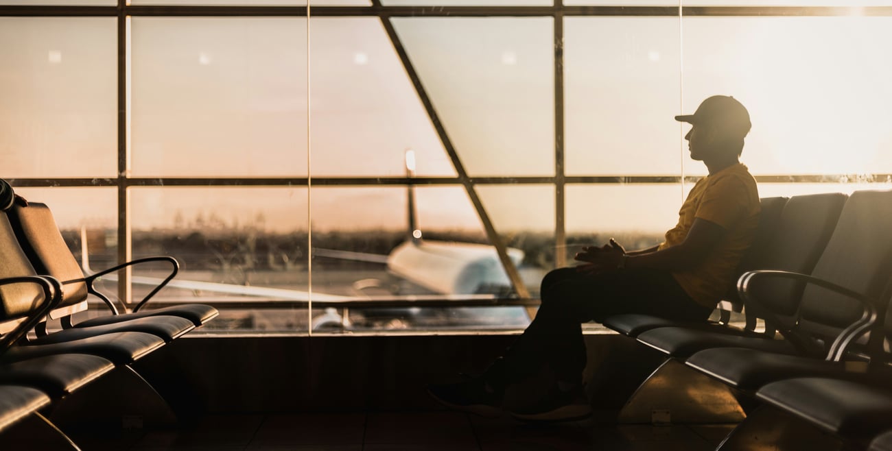 Person sitting alone in airport terminal with a plane out the window
